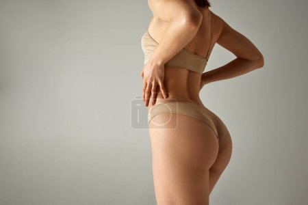 Photo for Cropped image of fit, slim female body, smooth buttocks. Model posing in underwear against grey studio background. Anti-cellulite care. Concept of body and health care, female beauty, wellness - Royalty Free Image