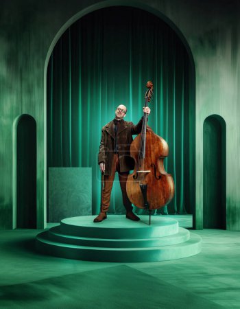 Photo for Male musician with glasses, in suit standing with double bass on green luxurious stage. Aesthetic vibe of music show. Concept of music, performance, art, talent show, inspiration. Poster - Royalty Free Image