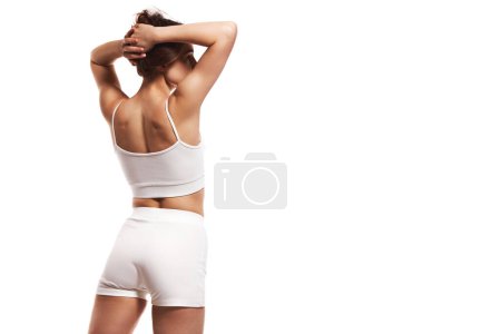 Photo for Cropped image of slim, tanned female body in comfortable underwear. Model standing with raised hands against white studio background. Concept of body and health care, sport, female beauty, wellness - Royalty Free Image
