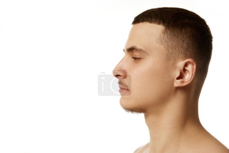Photo for Side view headshot of young brunette shirtless man posing against white studio background. Confidence and beauty. Concept of beauty procedures, male health, body care, spa treatment, hygiene. - Royalty Free Image