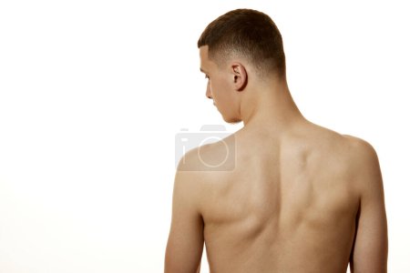Téléchargez les photos : Vue arrière portrait de jeune homme au dos sain posant sur fond de studio blanc. Santé et beauté. Concept de soins de beauté, santé masculine, soins du corps, soins spa, hygiène. - en image libre de droit