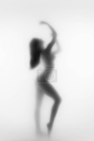Téléchargez les photos : Silhouette monochrome abstraite de figure féminine dansant, posant en arrière-plan flou. Art noir et blanc. Bien-être, grâce et équilibre. Concept d'esthétique corporelle, féminité, beauté, santé mentale - en image libre de droit