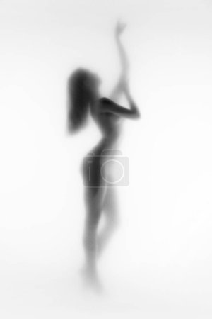 Téléchargez les photos : Image en noir et blanc. Silhouette de femme élégante et tendre posant nue. Image floue. Personnalité cachée. Concept d'esthétique corporelle, féminité, beauté, santé, art - en image libre de droit
