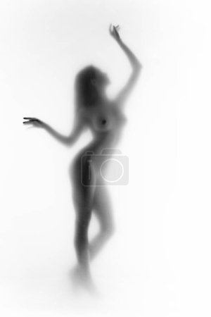 Téléchargez les photos : Silhouette monochrome et floue de la silhouette féminine avec les bras levés en mouvement. Noir et blanc. tendresse et sensualité. Concept d'esthétique corporelle, féminité, beauté, santé, art - en image libre de droit