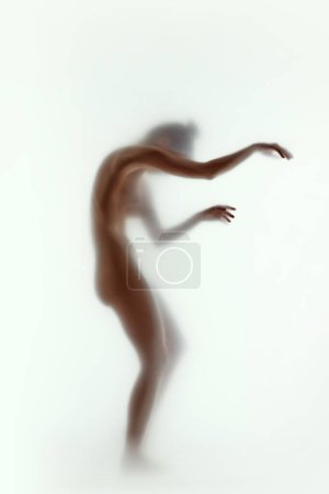 Téléchargez les photos : Paix intérieure et soins de soi. Silhouette floue de femme nue posant en pose dynamique sur fond clair. Concept d'esthétique corporelle, féminité, beauté, santé, art - en image libre de droit