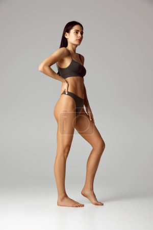 Photo for Beautiful, attractive woman posing in underwear looking away against grey studio background. Female model with perfect body shapes. Concept of beauty, spa procedures, dermatology treatments. Ad - Royalty Free Image
