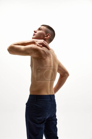 Photo for Shirtless handsome young man with muscular body, birthmark on shoulder posing in jeans isolated over white studio background. Concept of sportive lifestyle, body and heath care, youth - Royalty Free Image