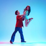 Poster for retro dance festival. Young stylish man and woman dancing retro dance against blue background in neon light. Concept of hobby, dance class, party, 50s, 60s culture, youth