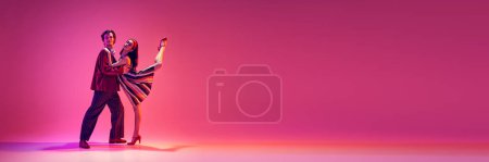Retro dance aesthetics. Elegant young man and woman dancing against pink background in neon light. Concept of hobby, dance class, party, 50s, 60s culture, youth. Banner. Empty space to insert text ad