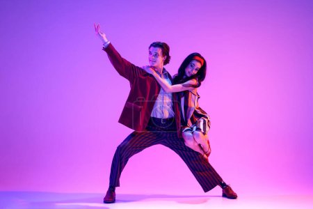 Photo for Artistic young man and woman in retro style clothes dancing boogie woogie against purple background in neon light. Aesthetics. Concept of hobby, dance class, party, 50s, 60s culture, youth - Royalty Free Image
