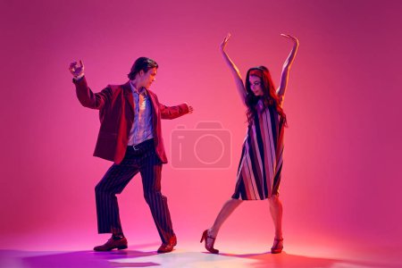 Photo for Young man and woman in stylish clothes dancing retro dance, boogie woogie against pink background in neon light. Concept of hobby, dance class, party, 50s, 60s culture, youth - Royalty Free Image
