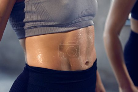 Close up of young woman with athletic body in sportswear wet after productive weightlifting training at gym. Concept of professional sportsman, healthy and active lifestyle, workout. Ad