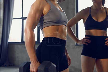 Cropped photo of young woman with athletic body in sportswear wet after productive weightlifting training at gym. Concept of professional sportsman, healthy and active lifestyle, workout. Ad