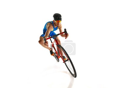 Téléchargez les photos : Image dynamique de l'homme concentré, athlète, cycliste en mouvement à vélo isolé sur fond de studio blanc. Concept de sport, mode de vie actif et sain, vitesse, endurance, passe-temps - en image libre de droit