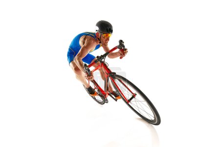 Téléchargez les photos : Image dynamique de l'homme concentré, athlète, cycliste en mouvement à vélo isolé sur fond de studio blanc. Concept de sport, mode de vie actif et sain, vitesse, endurance, passe-temps - en image libre de droit