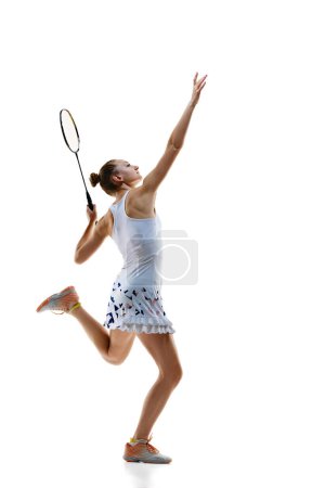 Téléchargez les photos : Image pleine longueur jeune fille sportive, joueur de badminton en mouvement servant navette avec raquette isolée sur fond blanc. Concept de sport professionnel, mode de vie actif, passe-temps, jeu - en image libre de droit