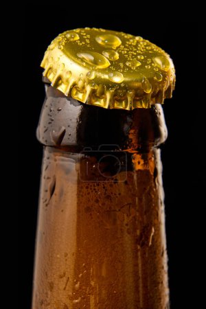 Téléchargez les photos : Gros plan de bouteille de bière brune avec capuchon de couleur or sur fond noir. Bulles bière mousseuse lager. Concept de boissons alcoolisées et non alcoolisées, rafraîchissements. Affiche, bannière pour la publicité - en image libre de droit