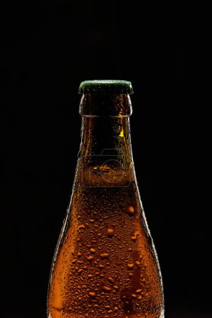 Photo for Close-up of brown beer bottle with green cap against black background. Bubbles lager foamy beer. Concept of alcohol and non-alcohol drinks, refreshment. Poster, banner for ad - Royalty Free Image