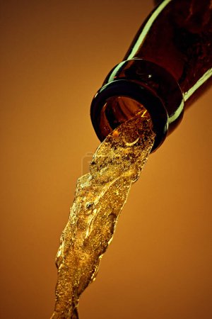 Foto de Primer plano de la botella de cerveza con cerveza fría lager vertiendo sobre el fondo amarillo. Bebida de fiesta. Concepto de bebidas alcohólicas y no alcohólicas, refresco. Póster, banner para anuncio - Imagen libre de derechos