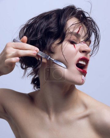 Photo for Artistic representation of modern problem. Addicting to plastic surgery and acceptance of self. Woman with scalpel on her face. Concept of modern beauty standards, plastic surgery, health, cosmetology - Royalty Free Image