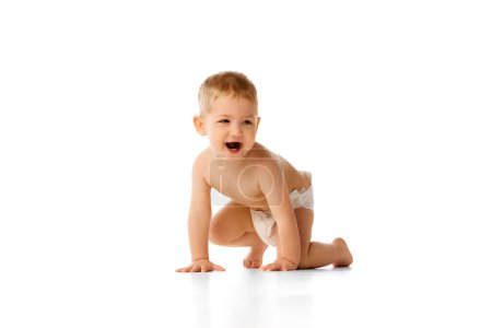 Photo for Happy little baby boy in diaper playing, crawling, smiling isolated over white studio background. Positive mood. Concept of childhood and family, care, parenthood, infancy and heath - Royalty Free Image
