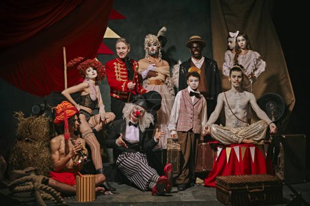 Photo for Diverse cast of vintage circus performers poses over dark retro circus backstage background. Promotional poster for upcoming performances. Concept of circus, theater, performance, show, retro and - Royalty Free Image