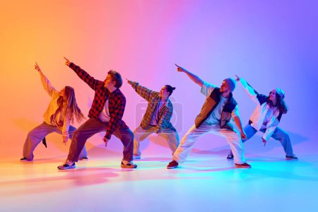 Photo for Group of five dancers in casual clothes performing with synchronized poses against gradient studio background in neon light. Concept of modern dance style, hobby, active lifestyle, youth culture - Royalty Free Image