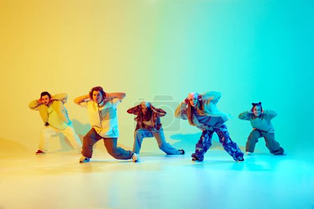 Photo for Dynamic performance of five talented dancers in motion, dancing modern dance over gradient green yellow background in neon light. Concept of modern dance style, hobby, active lifestyle, youth culture - Royalty Free Image