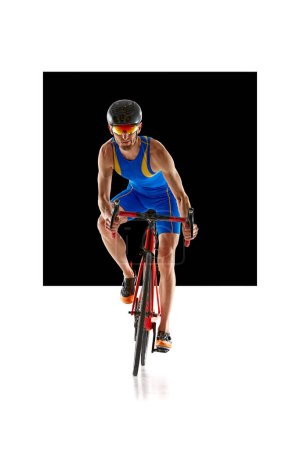 Téléchargez les photos : Image de face de l'homme, athlète en casque de sport et lunettes d'entraînement en mouvement sur vélo isolé sur fond blanc avec élément noir. Concept de sport, mode de vie actif et sain, endurance - en image libre de droit