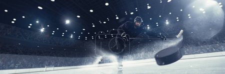 Foto de Imagen dinámica del hombre competitivo, jugador de hockey profesional en uniforme en movimiento durante el torneo, con disco en 3d hacer pista de hielo. Concepto de deporte, competición, partido, juego, acción, torneo - Imagen libre de derechos