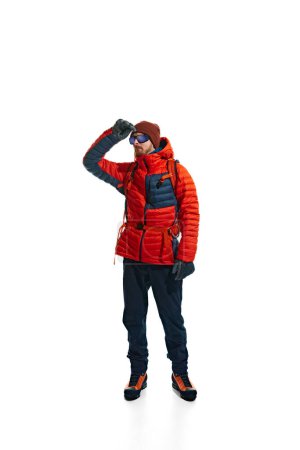 Photo for Outdoor apparel ad showcasing the warmth and versatility of climbing gear. Man in jacket with backpack isolated on white background. Concept of active lifestyle, tourism, mountaineering, sport, travel - Royalty Free Image