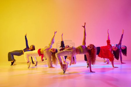 Téléchargez les photos : Pose dynamique. Jeunes femmes dansant contemp, exécutant des styles de danse modernes sur fond de dégradé sous la lumière du néon. Concept de jeunesse, danse de rue, danse contemporaine, moderne, dynamique - en image libre de droit