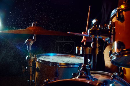 Photo for Close-up of drum set on black background with flashlights. Male musician playing drums. Live performance. Concept of music, instruments, concert, sound, equipment, festival - Royalty Free Image