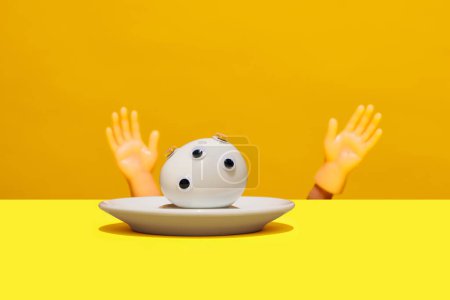 Photo for Boiled egg with googly eyes on it in small round plate and toy hands lying on yellow orange background. Artistic food representation. Concept of food pop art photography, creativity, quirky style - Royalty Free Image