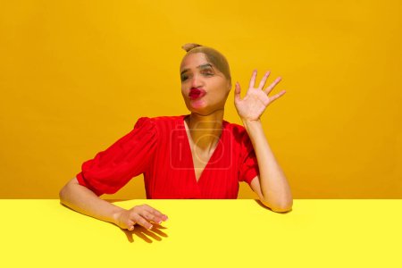 Junge Frau mit Strumpf über dem Kopf und verschmiertem Lippenstift-Make-up, das vor gelbem Hintergrund witzige Mienen macht. Konzept der Food-Pop-Art-Fotografie, Kreativität, skurriler Stil