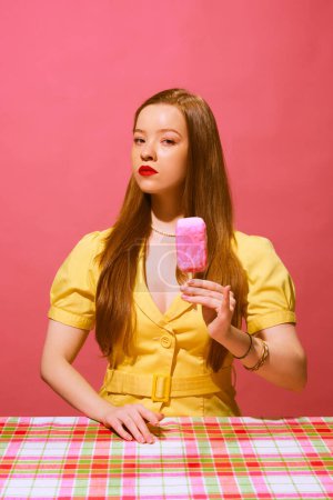 Photo for Young redhead woman in yellow dress, with serious face holding fake ice cream made of soap against pink background. Cleaning product line. Concept of pop art photography, creativity, surrealism - Royalty Free Image