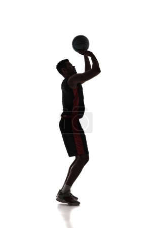 Photo for Full-length of young concentrated man, basketball player standing and throwing ball into basketball hoop isolated on white background. Concept of professional sport, competition, game, tournament - Royalty Free Image