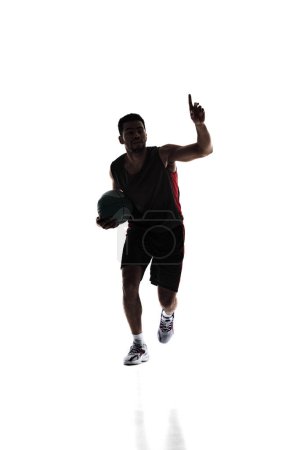 Photo for Young sportive man, basketball player in uniform with ball training during game isolated on white background. Silhouette. Concept of professional sport, competition, game, tournament, action - Royalty Free Image