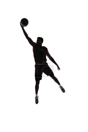 Photo for Slam dunk. Silhouette of basketball player in motion during game throwing ball in a jump isolated on white background. Silhouette. Concept of professional sport, competition, game, tournament, action - Royalty Free Image