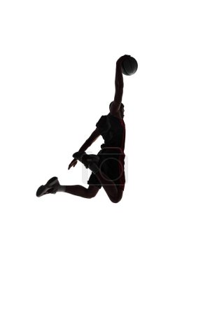 Photo for Slam dunk. Back view silhouette of young man, basketball player in motion throwing ball during game isolated on white background. Concept of professional sport, competition, game, tournament, action - Royalty Free Image