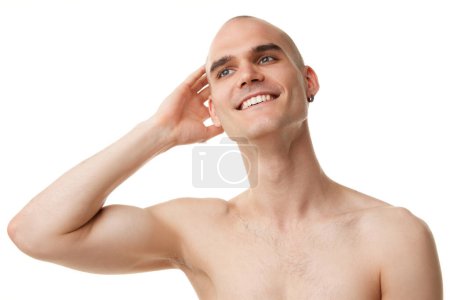 Téléchargez les photos : Portrait d'un beau jeune homme souriant à la tête chauve, aux dents blanches et à la peau immaculée isolé sur fond de studio blanc. Concept de soins de la peau, beauté masculine, bien-être, cosmétique, auto-soin - en image libre de droit
