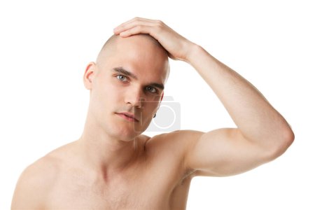 Téléchargez les photos : Portrait de beau jeune homme à tête chauve, peau immaculée prenant soin après visage sur salle de bain isolée sur fond de studio blanc. Concept de soins de la peau, beauté masculine, bien-être, cosmétique, auto-soin - en image libre de droit