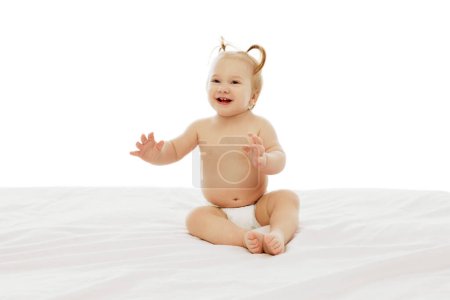 Photo for Portrait of happy little baby girl, toddlers with two ponytails sitting in diaper with playful happy face isolated on white background. Concept of childhood, care, health, well-being, parenthood - Royalty Free Image