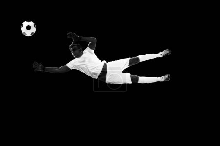 Photo for Determined sportsman, football player in motion with ball, training isolated on black background. Monochrome. Concept of professional sport, game, competition, tournament, action, active lifestyle - Royalty Free Image