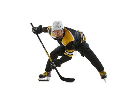 Foto de Hombre enfocado determinado, jugador de hockey en uniforme y casco de pie con palo, entrenamiento aislado sobre fondo blanco. Concepto de deporte profesional, competición, juego, torneo - Imagen libre de derechos