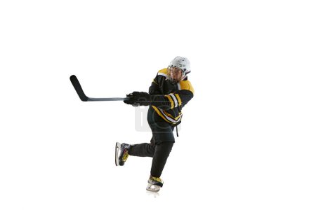 Téléchargez les photos : Joueur de hockey masculin en mouvement pendant le match avec bâton isolé sur fond blanc. Se sentir compétitif et concentré. Concept de sport professionnel, compétition, jeu, tournoi - en image libre de droit