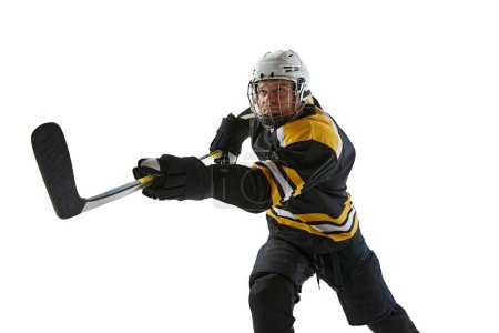 Téléchargez les photos : Homme compétitif, concentré, joueur de hockey avec bâton en mouvement pendant le match, s'entraînant isolé sur fond blanc. Concept de sport professionnel, compétition, jeu, tournoi - en image libre de droit