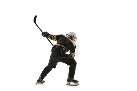 Téléchargez les photos : Homme déterminé, joueur de hockey se préparant pour la compétition en mouvement, s'entraînant isolé sur fond blanc. Concept de sport professionnel, compétition, jeu, tournoi, mode de vie actif - en image libre de droit