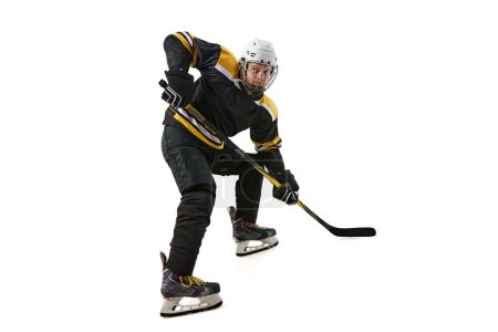Foto de Atleta masculino, jugador de hockey con uniforme negro y entrenamiento de casco, compitiendo aislado sobre fondo blanco. Concepto de deporte profesional, competición, juego, torneo, estilo de vida activo - Imagen libre de derechos