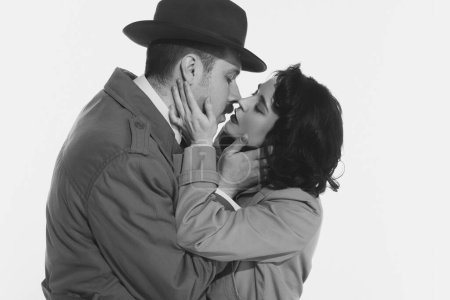 Photo for Portrait of happy young couple, man and woman in retro-styled clothes, coats standing and kissing. Monochrome image. Concept of retro and vintage, fashion, romance, relationship - Royalty Free Image